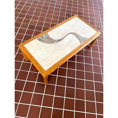 a coffee table with an artistic design on the top is shown in front of a tiled floor