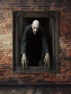 a creepy looking man standing in a window with his hands on the frame and eyes open