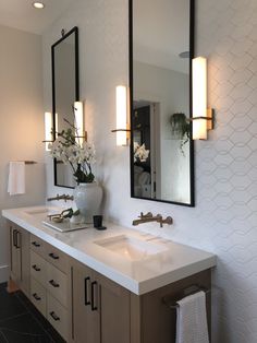 a bathroom with two sinks, mirrors and lights on the wall above them is shown