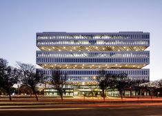 an office building lit up at night with lights shining on the facade and trees in front