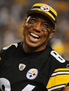 a football player with his face painted in yellow and black, smiles at the camera