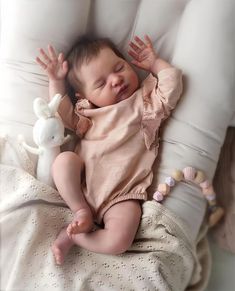 a baby laying on top of a bed next to a stuffed animal