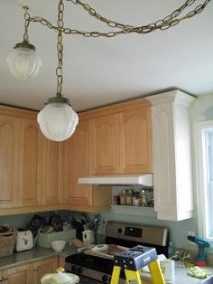 a kitchen that has some lights hanging from it's ceiling above the stove top