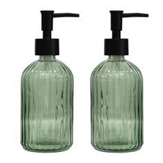 two green glass soap dispensers with black plastic caps on each one side