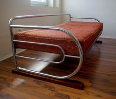 a metal bed frame sitting on top of a hard wood floor next to a window