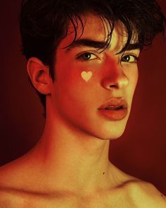 a man with no shirt on posing in front of a red background and white heart painted on his face