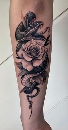 a woman's leg with a snake and rose tattoo on it, in black and white