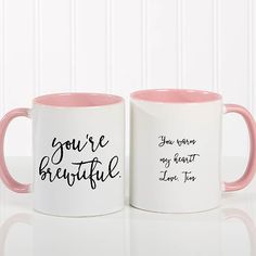 two pink and white coffee mugs with the words you're beautiful on them