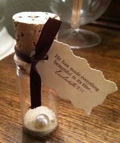 a message in a bottle with a pearl on the bottom and a ribbon tied around it