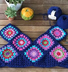 a crocheted pot holder with yarn and flowers on it next to a plant