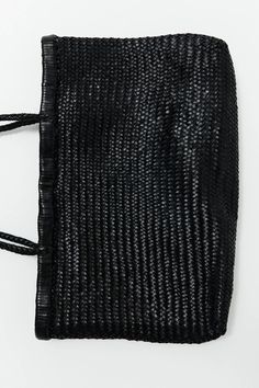 a black woven bag on a white surface