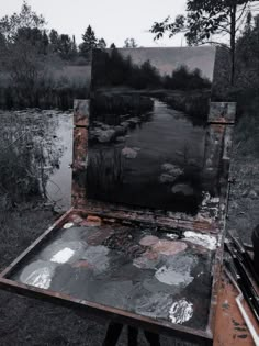 an artist's easel sitting in the middle of a field filled with water