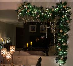 a decorated christmas tree in front of a mirror with candles on the table and other decorations around it