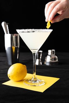 a person is squeezing lemon into a cocktail