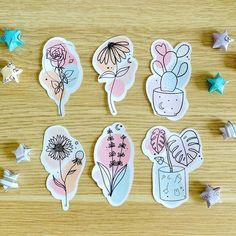 six stickers with flowers and plants in them on top of a wooden table next to stars