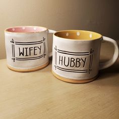 two coffee mugs sitting on top of a wooden table