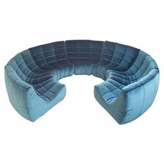 a blue curved couch sitting on top of a white floor