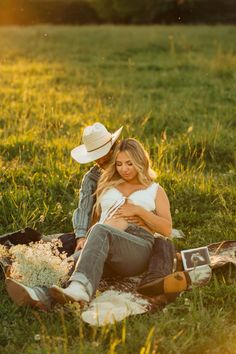 a woman sitting on top of a blanket next to a man in a cowboy hat