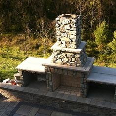 an outdoor stone oven with benches and trees in the background