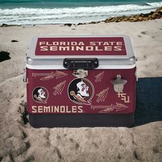 a cooler sitting on top of a sandy beach next to the ocean with florida state symbols