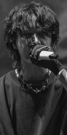 a man with curly hair holding a microphone to his mouth