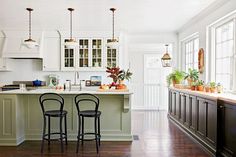 the kitchen has two bar stools in front of the counter and an island with plants on it