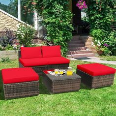 an outdoor furniture set with red cushions on the grass in front of a brick house