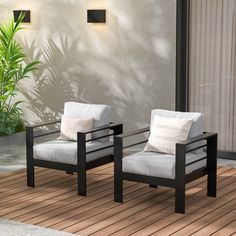 two white chairs sitting on top of a wooden floor next to a plant and wall