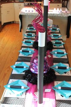 a long table is decorated with blue, pink and black paper plates and napkins