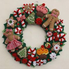 a christmas wreath made out of felt and decorated with gingerbreads, pretzels, candy canes, cookies, and other holiday decorations