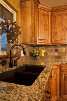 a kitchen with granite counter tops and wooden cabinets, including a black double basin sink