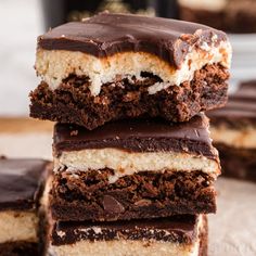 three pieces of chocolate cake with white and brown frosting on top are stacked up