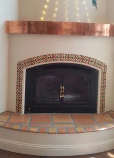 a fireplace with an ornate mantle and tiled hearth