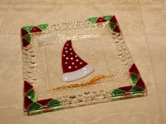 a glass plate with a red and green christmas hat on the bottom, sitting on a tile floor