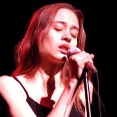 a woman singing into a microphone on stage