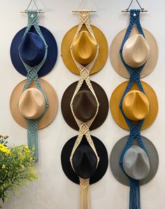 several hats are hanging on the wall with tassels attached to each hat and string