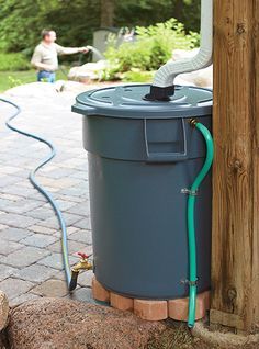 a blue trash can sitting next to a wooden pole with a hose attached to it