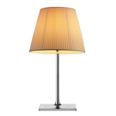 a lamp that is sitting on top of a metal stand with a beige shade over it