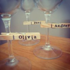 three wine glasses sitting on top of a wooden table with name tags attached to them