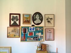 the wall is covered with many framed pictures and art work, including paintings on it