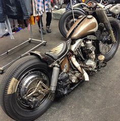 two motorcycles parked next to each other in a parking lot with people standing around them