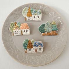 four embroidered houses on a plate