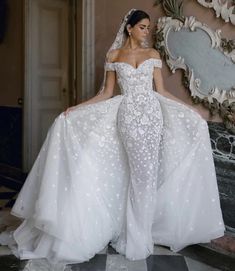 a woman in a wedding dress standing next to a mirror and looking at the camera