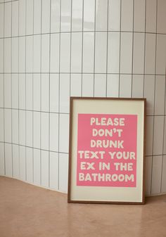 a pink and white sign sitting on top of a counter next to a tiled wall