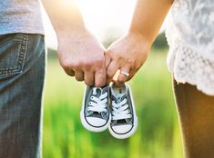 two people holding hands while standing next to each other in front of green grass and sunlight