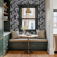 a window seat in the corner of a room with a table and pillows on it