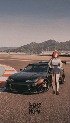 a woman standing next to a black car on top of a tarmac with mountains in the background