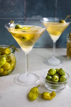 three martini glasses filled with olives on a table