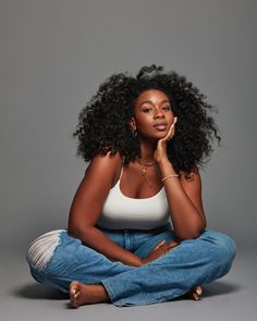 a woman sitting on the floor with her hand under her chin