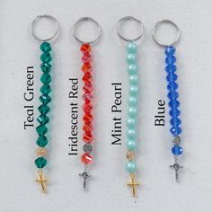 four different colored rosarys with cross charms on each beaded keychain, and the words blue, white, red, green, and multi - colored beads